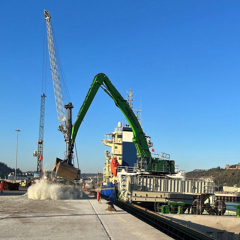 Cargo vessel Aasfjord unloading grain onto quayside at Port of Dover against blue sky