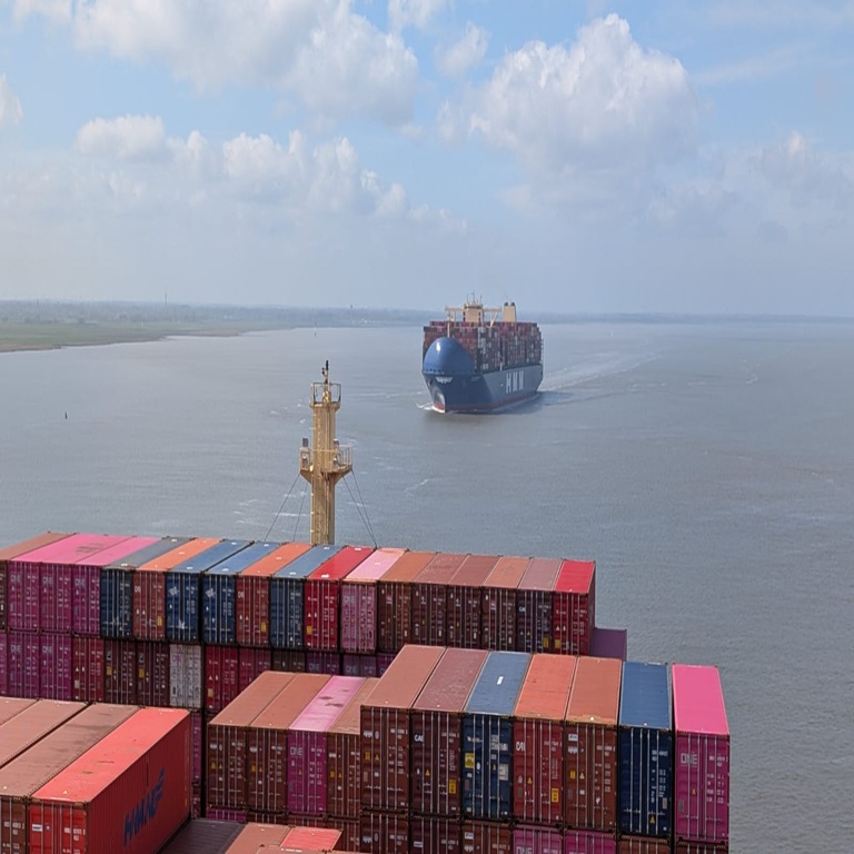 View from bridge of container ship at sea showing containers loaded at front of ship and another container ship approaching